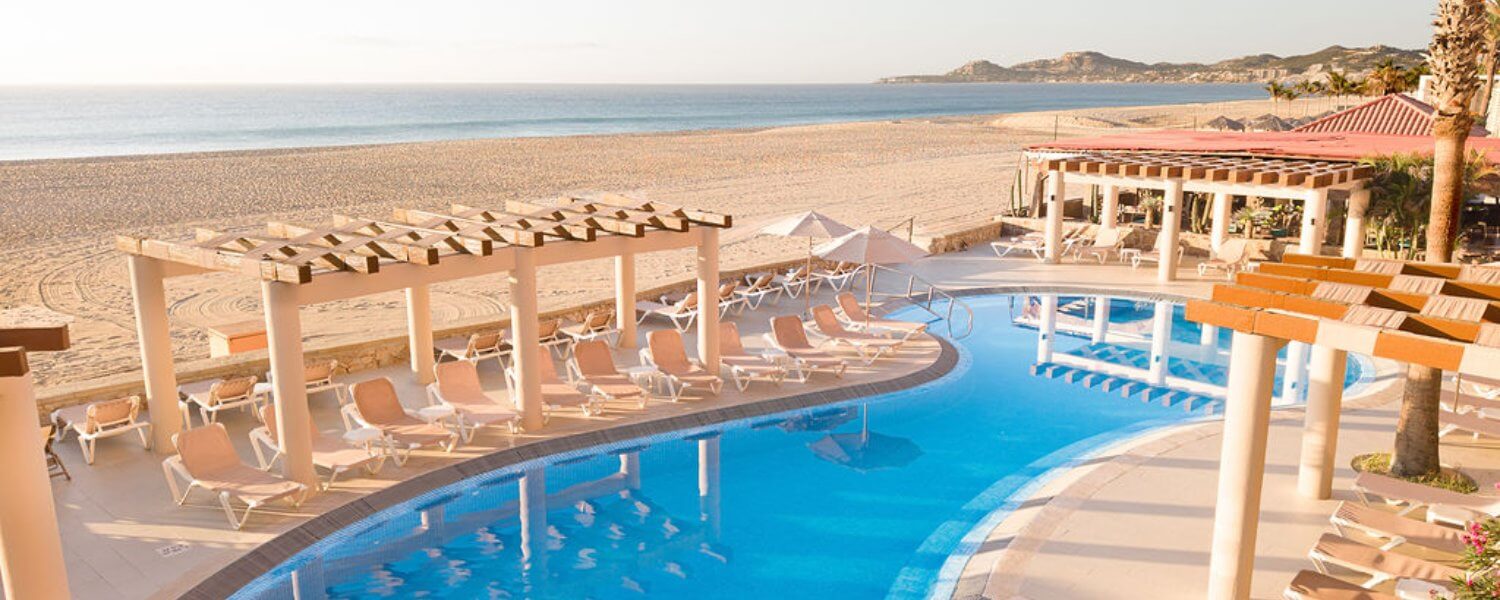 Quiet pool with loungers and palapas on the beach, facing the Sea of Cortez