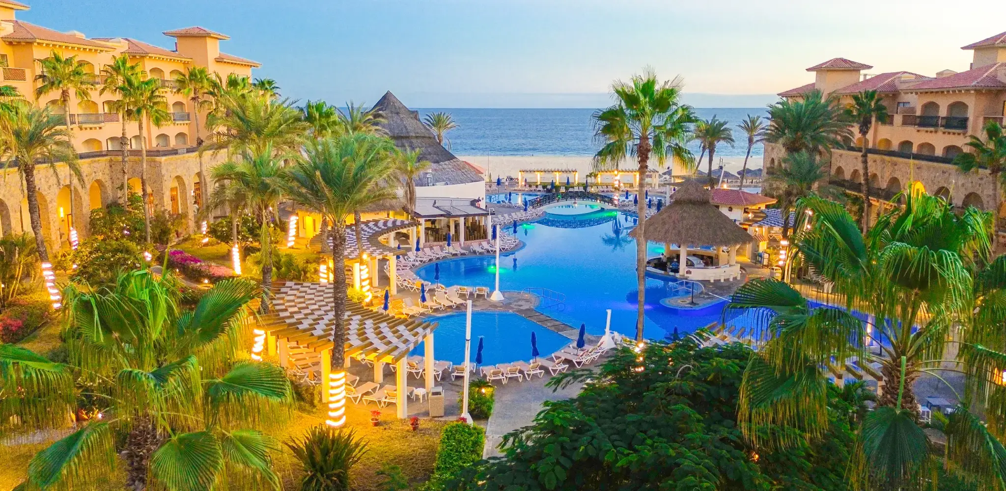 Royal Solaris Los Cabos at dusk: palm gardens and pools facing the Sea of Cortez